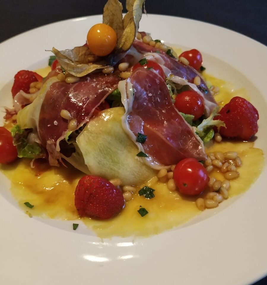 Amanida de fruites, maduixes, tomàquet, enciam, litxi, pinyons i pernil ibèric.
