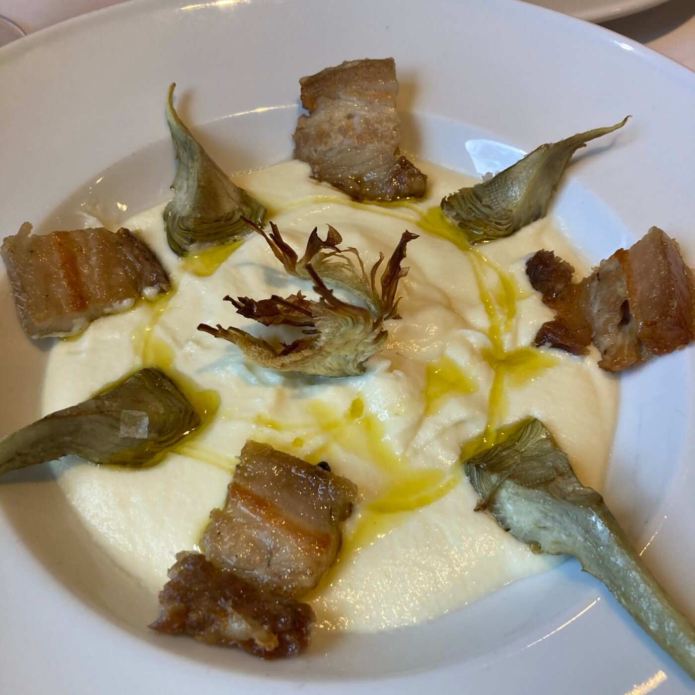 Textura de coliflor amb oli d’oliva verge extra, xips de carxofa i cansalada ibèrica confitada